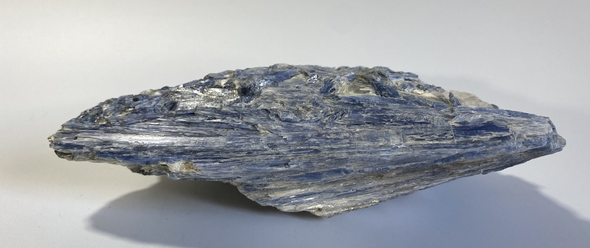 Piatra bruta din mineral de cianit pe fundal alb sub lumina naturala