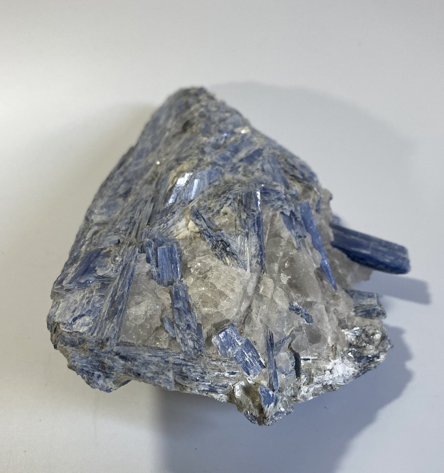 Piatra bruta din mineral de cianit pe fundal alb sub lumina naturala
