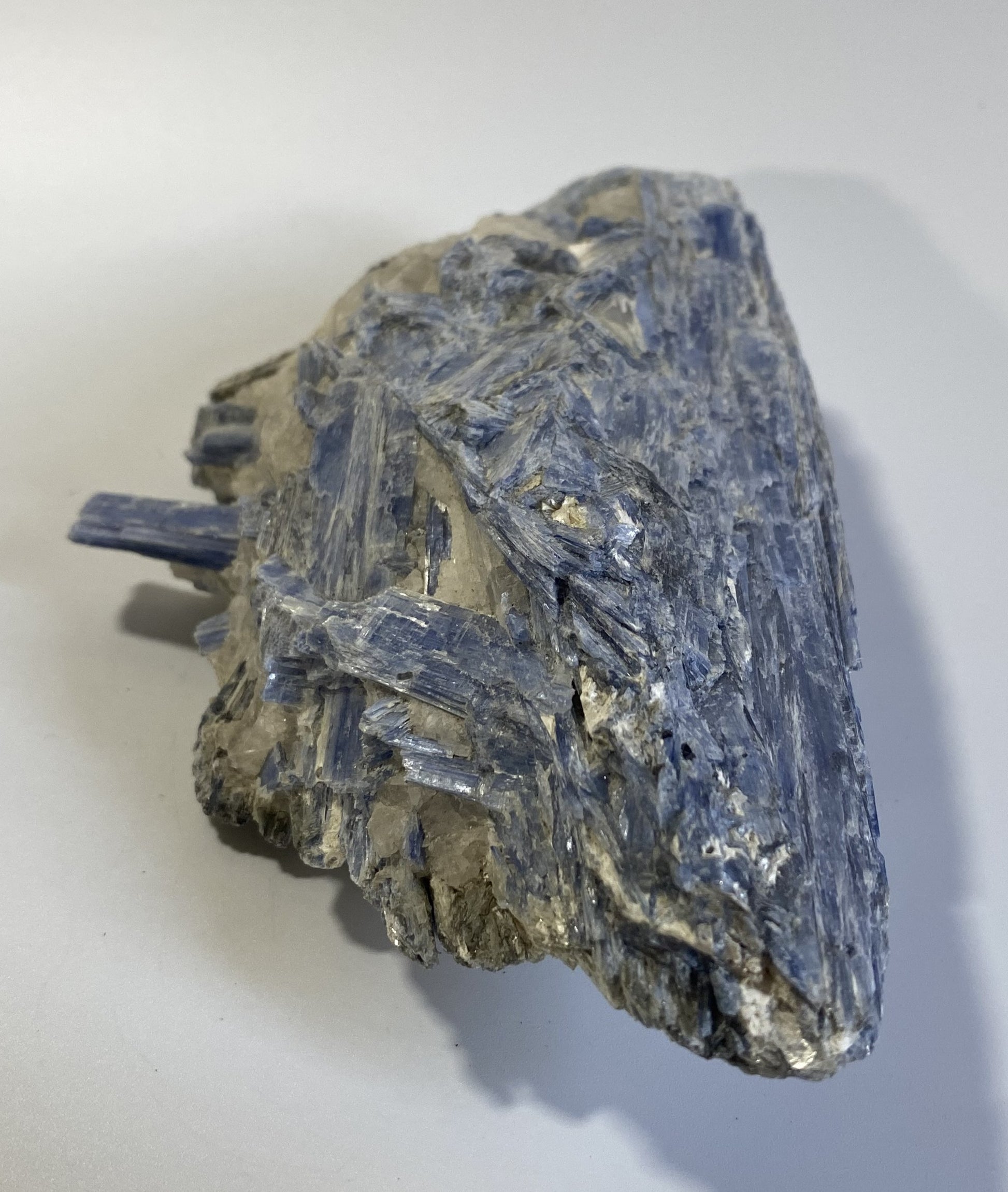 Piatra bruta din mineral de cianit pe fundal alb sub lumina naturala