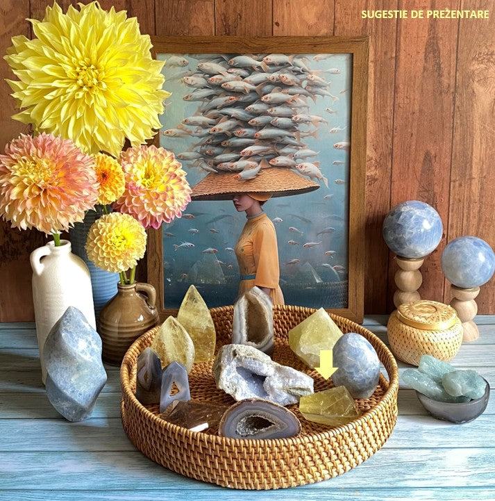Poligonal shaped Citrin gemstone displayed in a wicker basket with decorative flowers and artwork background