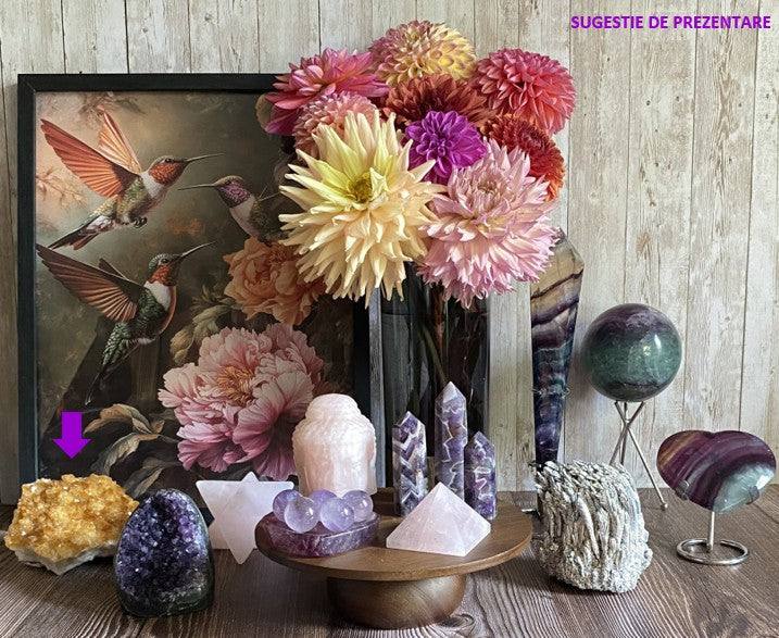 Fragment geoda din Citrin portocaliu pe masa decorată cu flori și cristale diverse