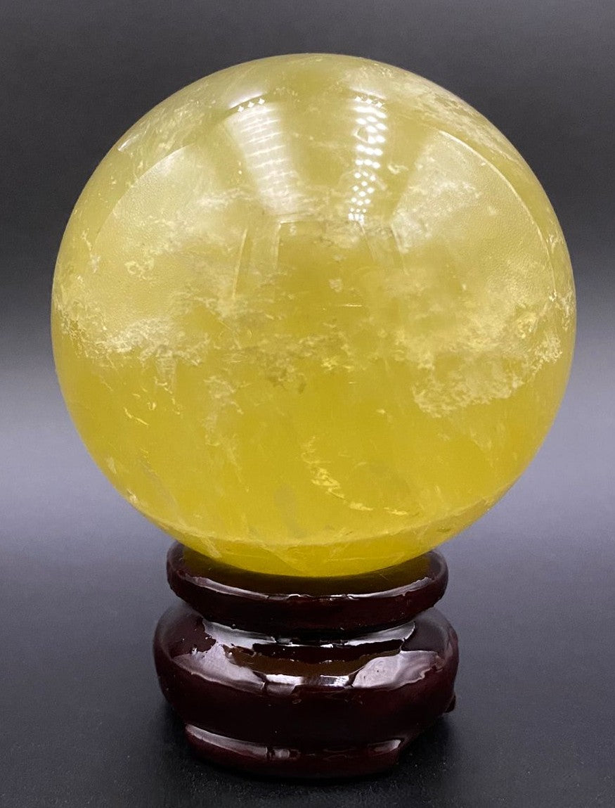 Sfera din cristal de citrin pe suport din lemn cu fundal negru