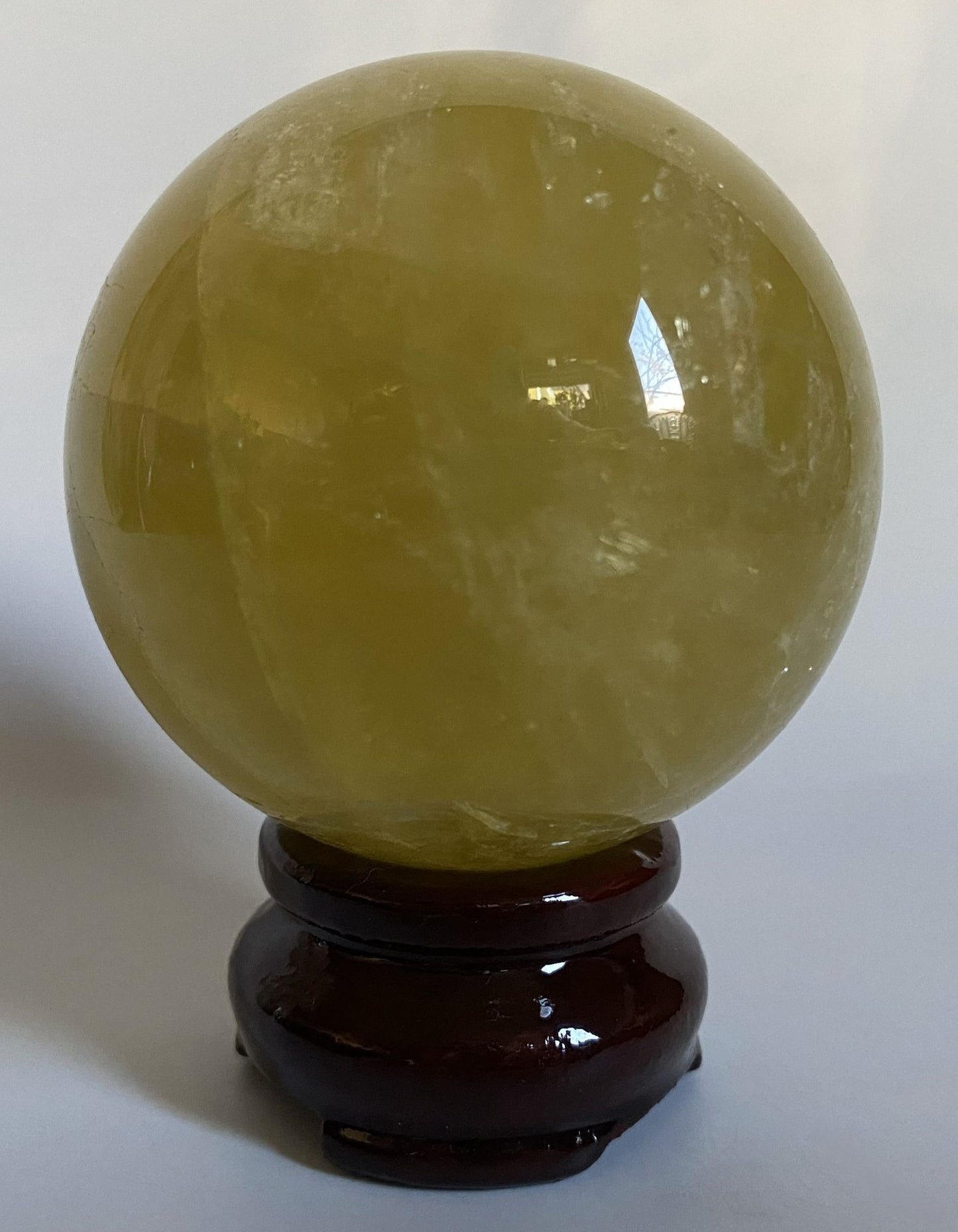 Sfera din cristal de citrin pe suport din lemn cu fundal alb