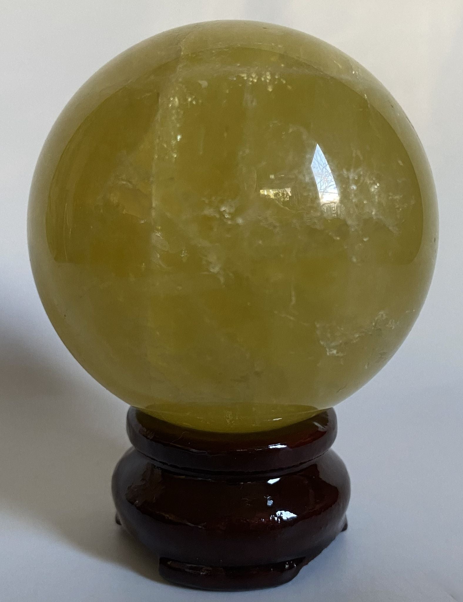 Sfera din piatra semipretioasa de citrin pe suport din lemn cu fundal alb