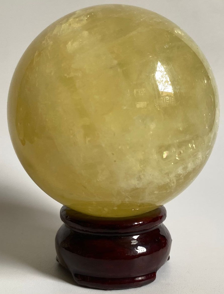Sfera din cristal de citrin pe suport din lemn cu fundal alb