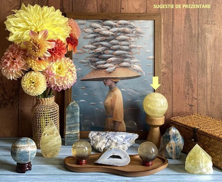 Sfera din Citrin pe suport negru printre cristale si decor floral pe fundal lemn