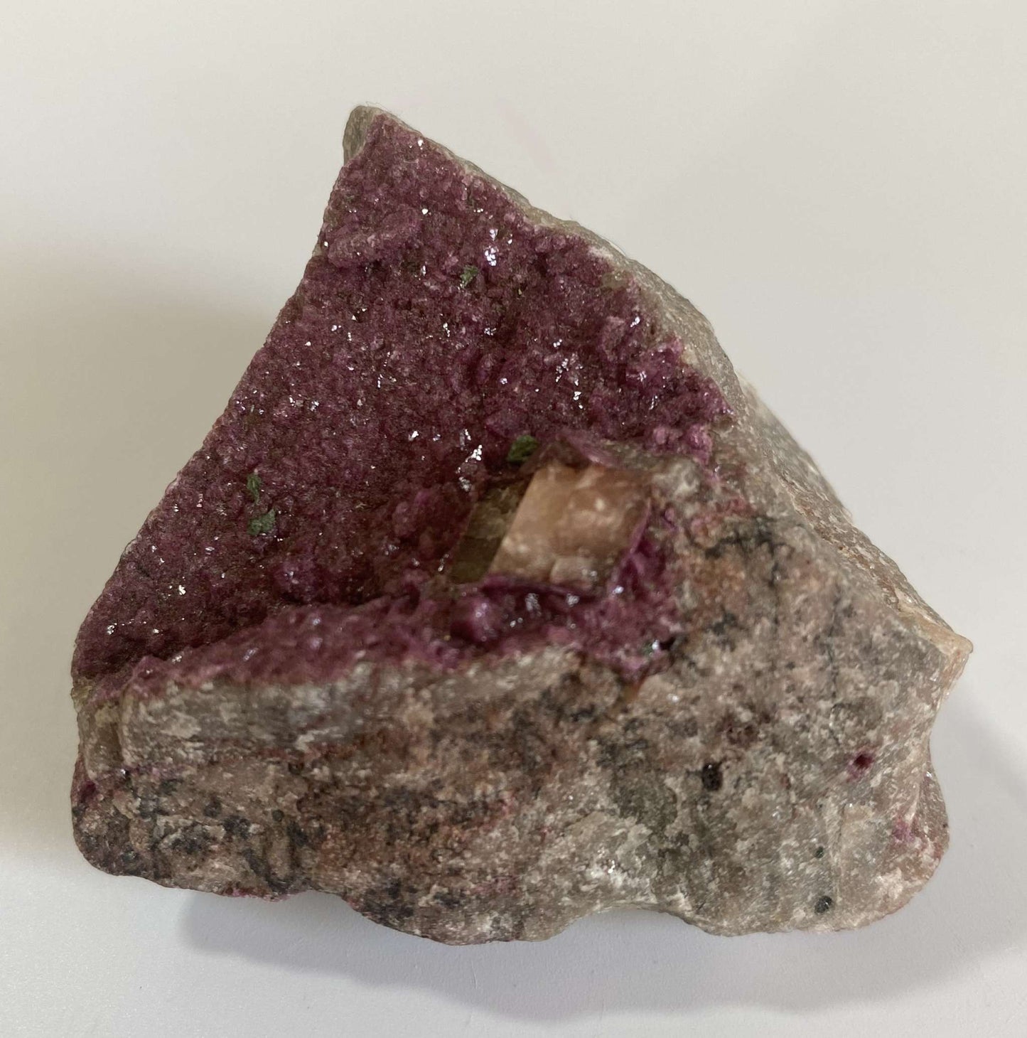 Cobaltocalcit mineral specimen with purple crystals on rough stone base