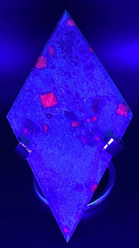 Romb din piatra semipretioasa de corindon in fucsit pe suport metalic sub lumina UV