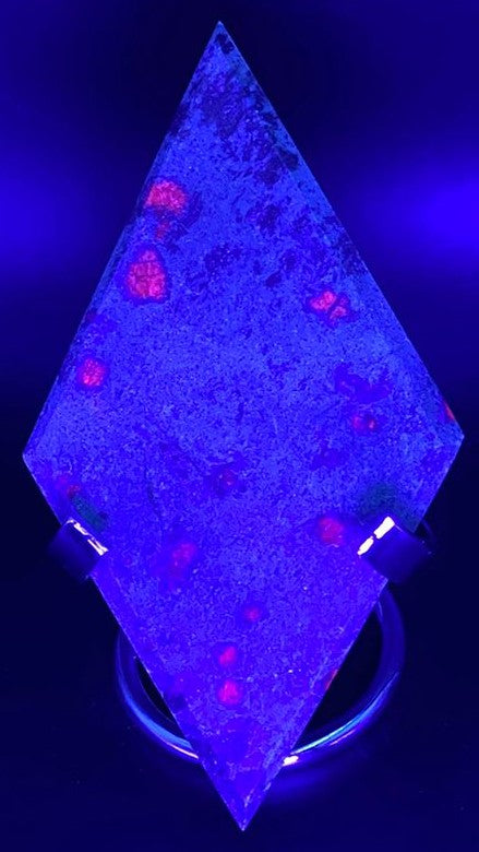 Romb din cristal de corindon in fucsit pe suport metalic sub lumina UV