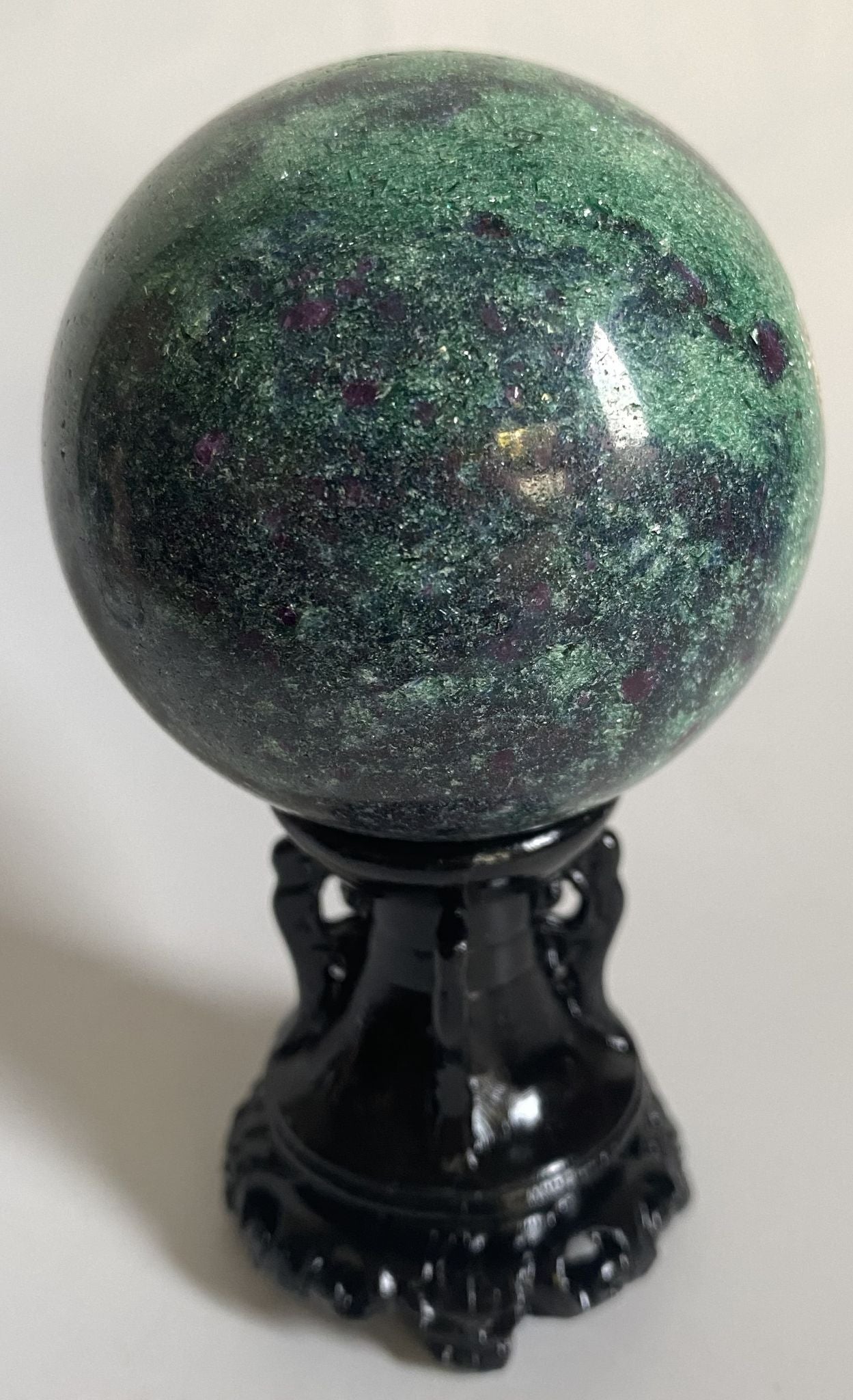 Sfera din cristal de corindon in fucsit pe suport decorativ cu fundal alb