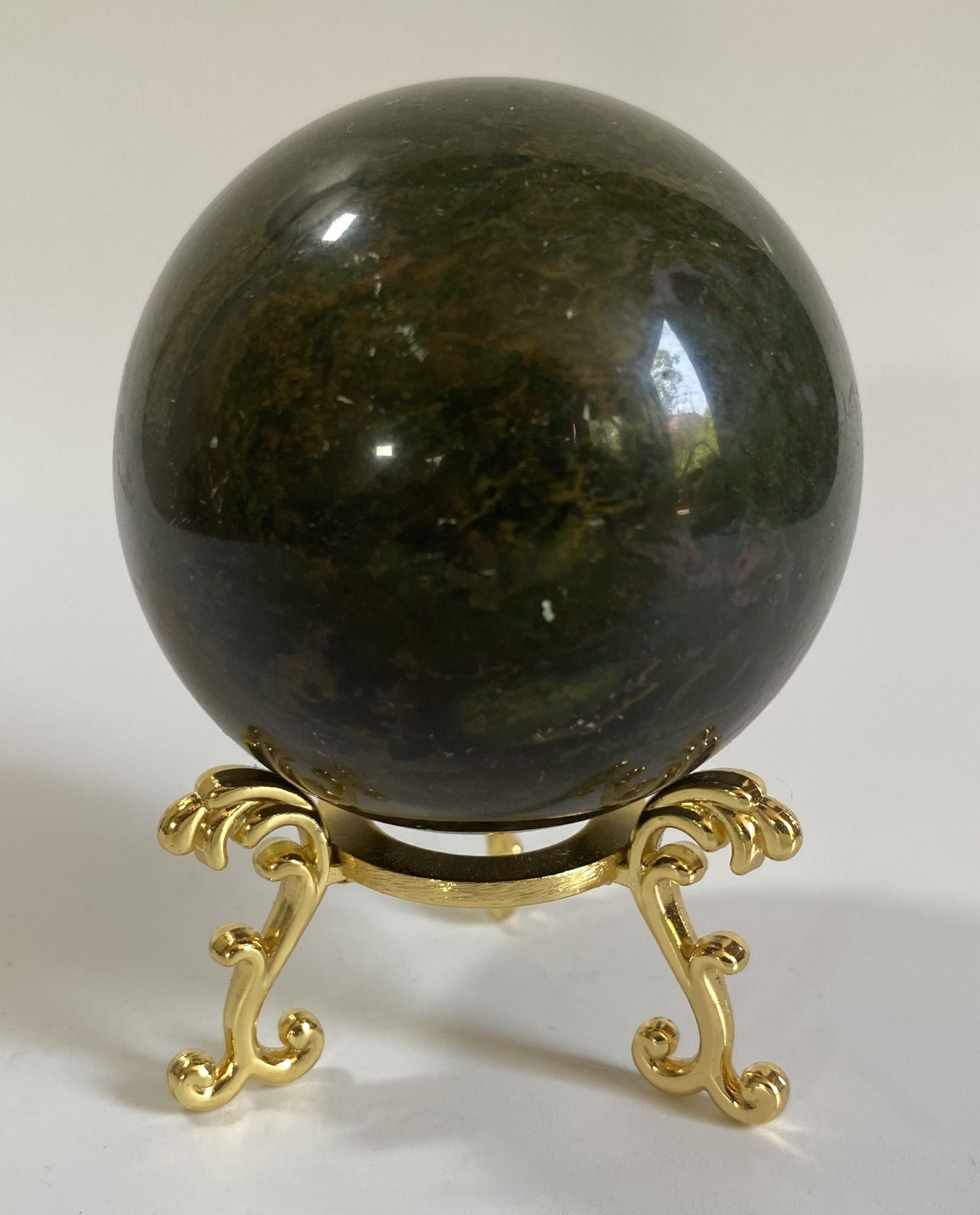 Sfera din cristal de corindon rosu pe suport metalic cu fundal alb