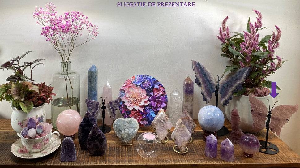 Cuart Capsuna butterfly gemstone with metal stand displayed among crystals and plants on wooden surface