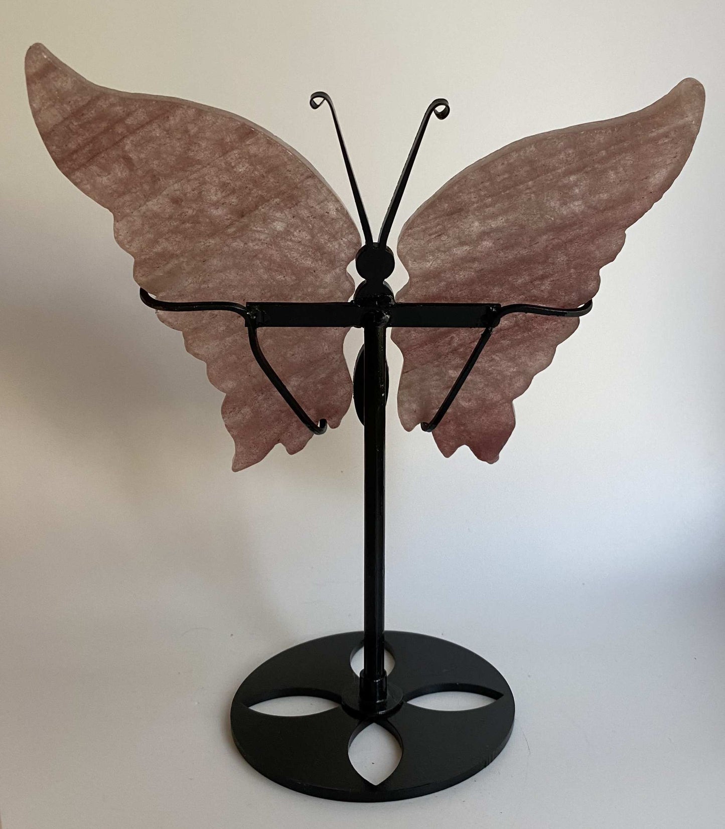 Butterfly sculpture made of strawberry quartz on a black metal stand with Cuart Capsuna stone wings