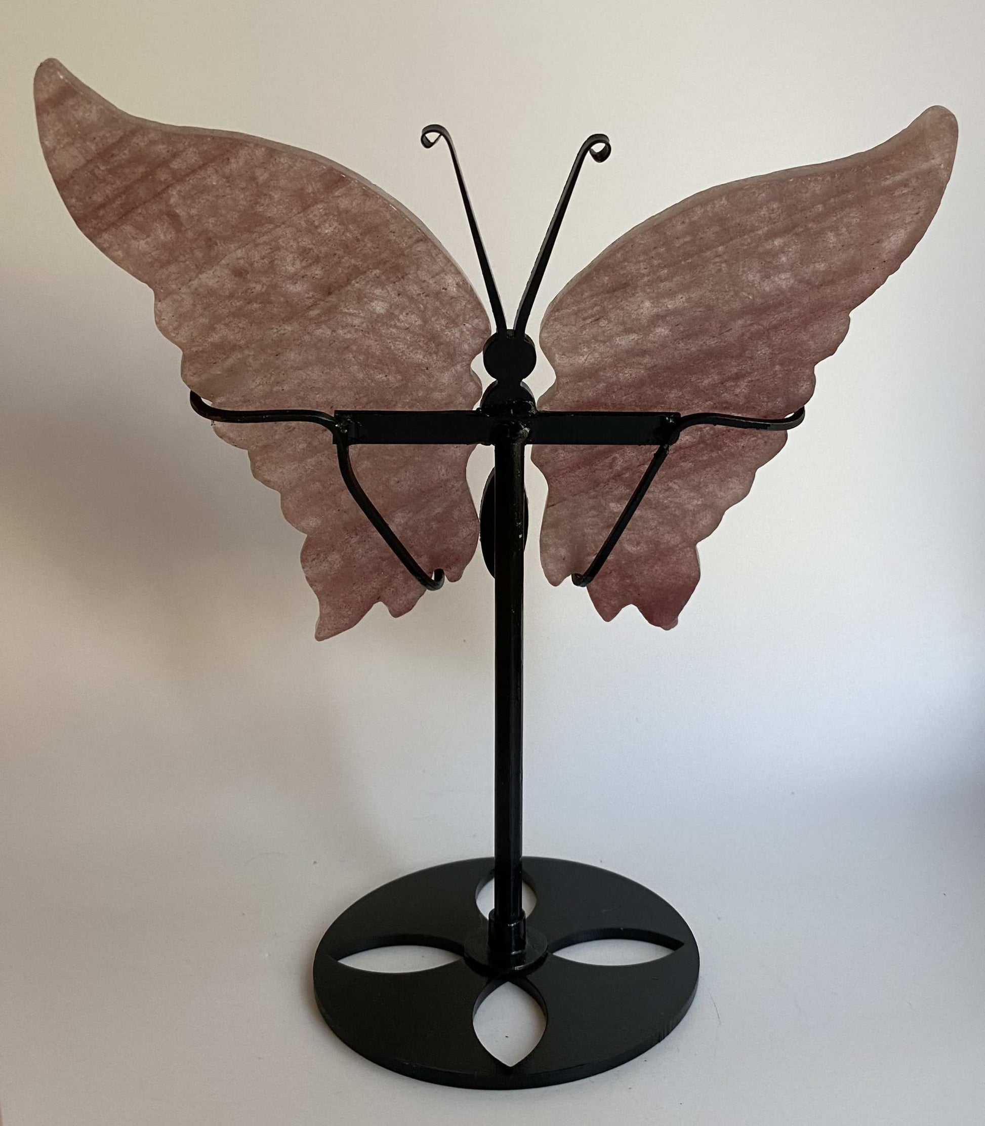 Butterfly sculpture made of strawberry quartz on a black metal stand with Cuart Capsuna stone wings