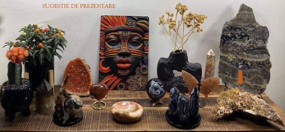 Cluster din Citrin portocaliu pe suport negru, aranjat pe masă printre alte cristale și decorațiuni.