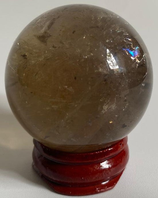 Sfera din cristal de cuart fumuriu pe suport din lemn cu fundal alb