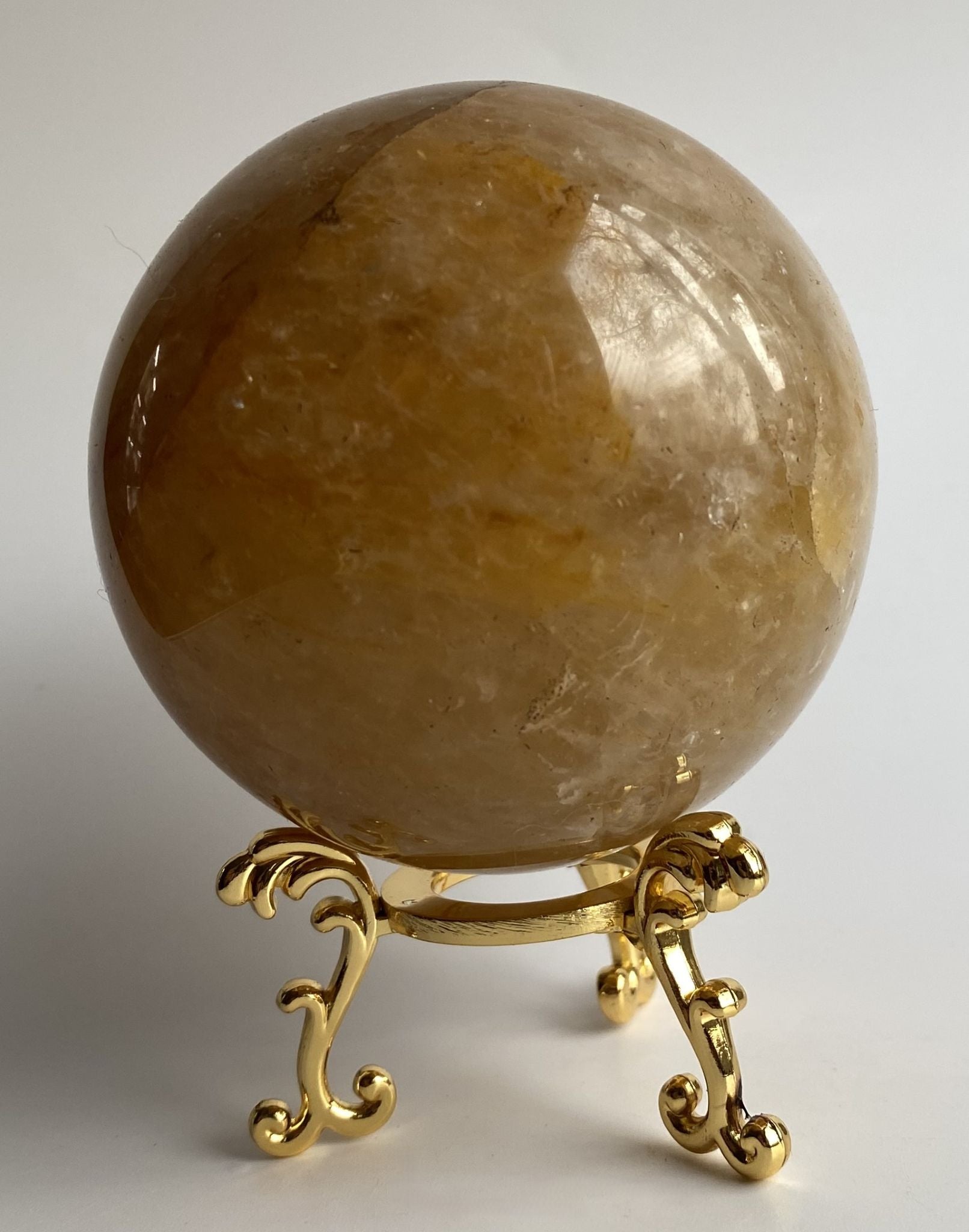 Sfera de 7.2cm din cristal de vindecatorul auriu pe suport metalic cu fundal alb
