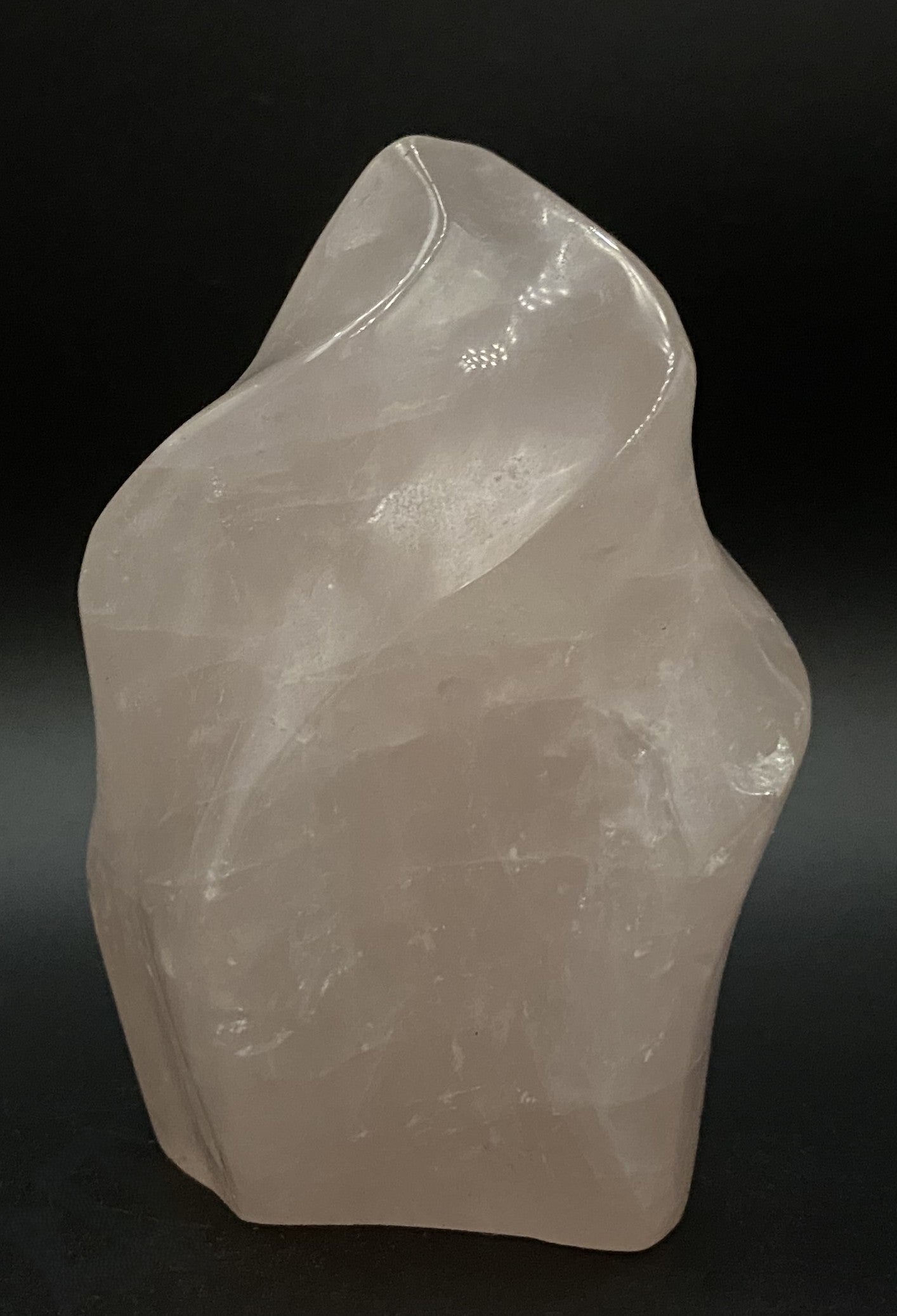 Sculptura din cristal de cuart roz pe fundal negru sub lumina artificiala