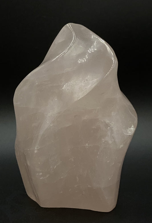 Sculptura din cristal de cuart roz pe fundal negru sub lumina artificiala