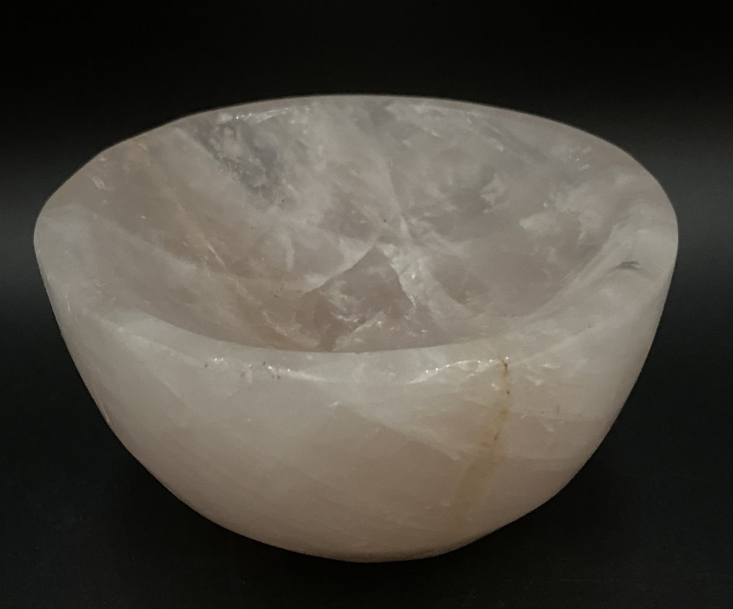 Bol din cristal de cuart roz pe fundal negru sub lumina artificiala