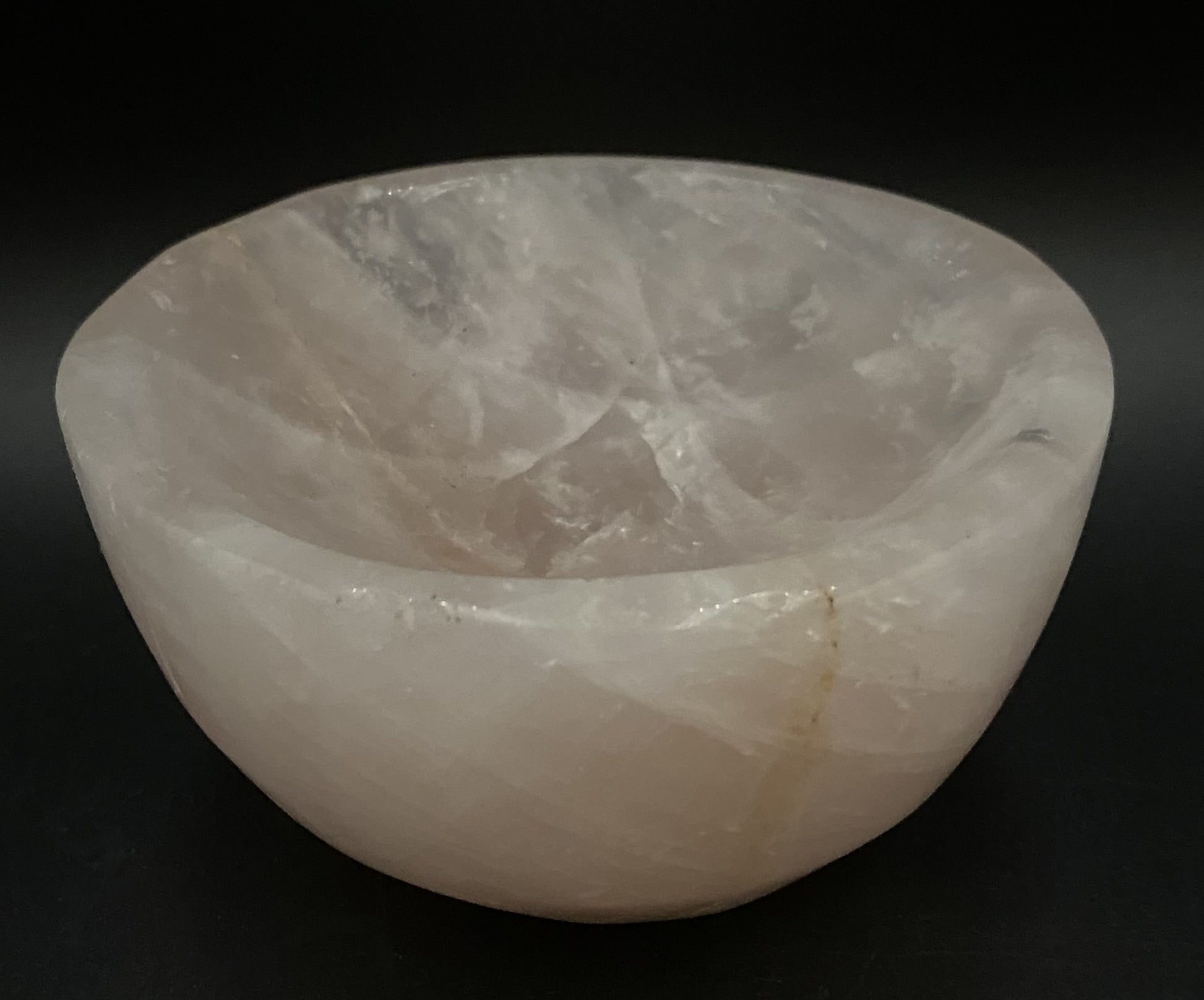 Bol din cristal de cuart roz pe fundal negru sub lumina artificiala