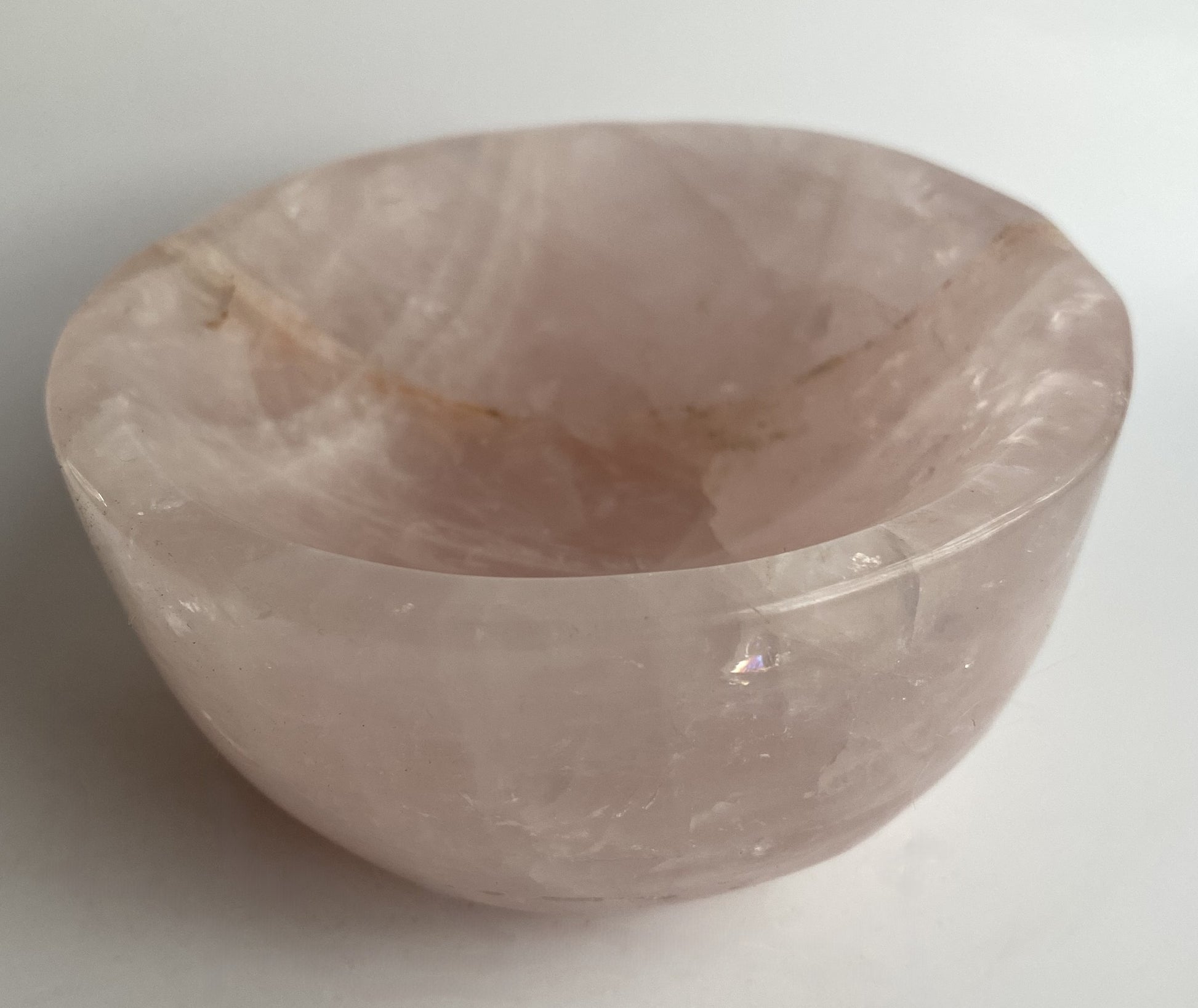 Bol din cristal de cuart roz pe fundal alb sub lumina naturala