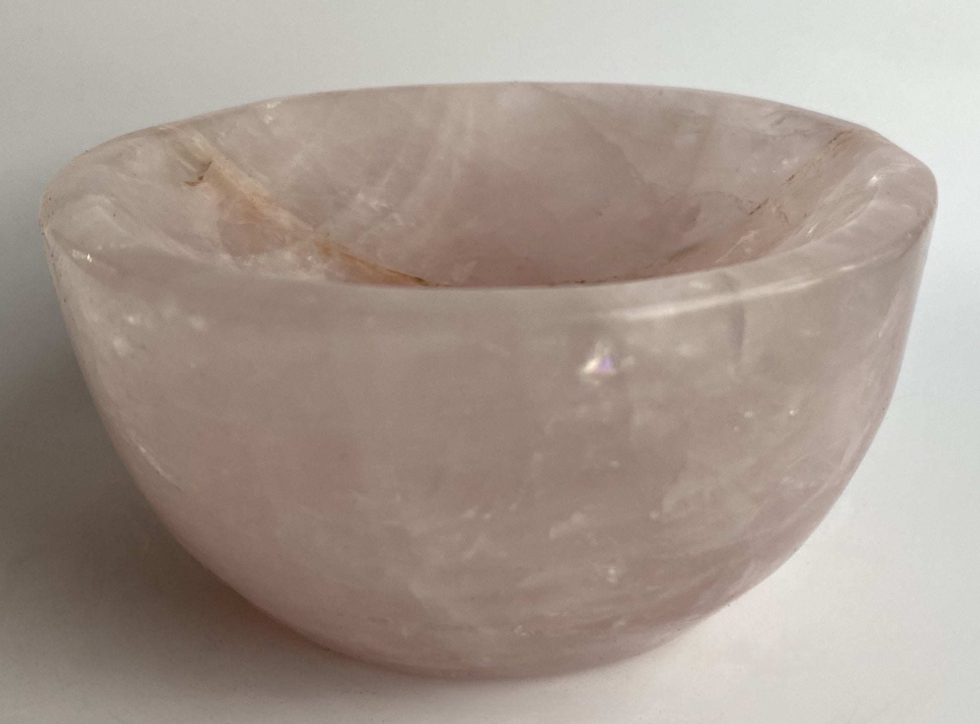 Bol din cristal de cuart roz pe fundal alb sub lumina naturala