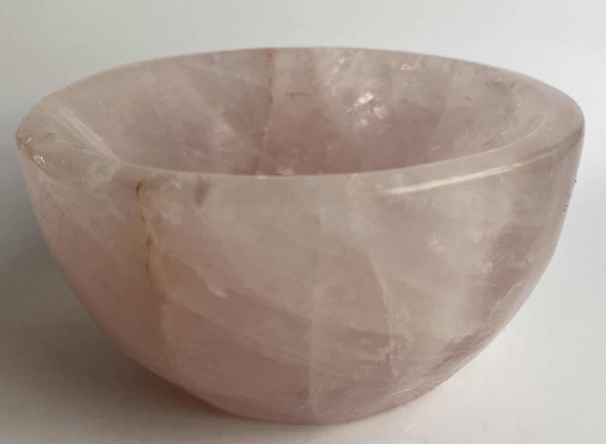 Bol din cristal de cuart roz pe fundal alb sub lumina naturala