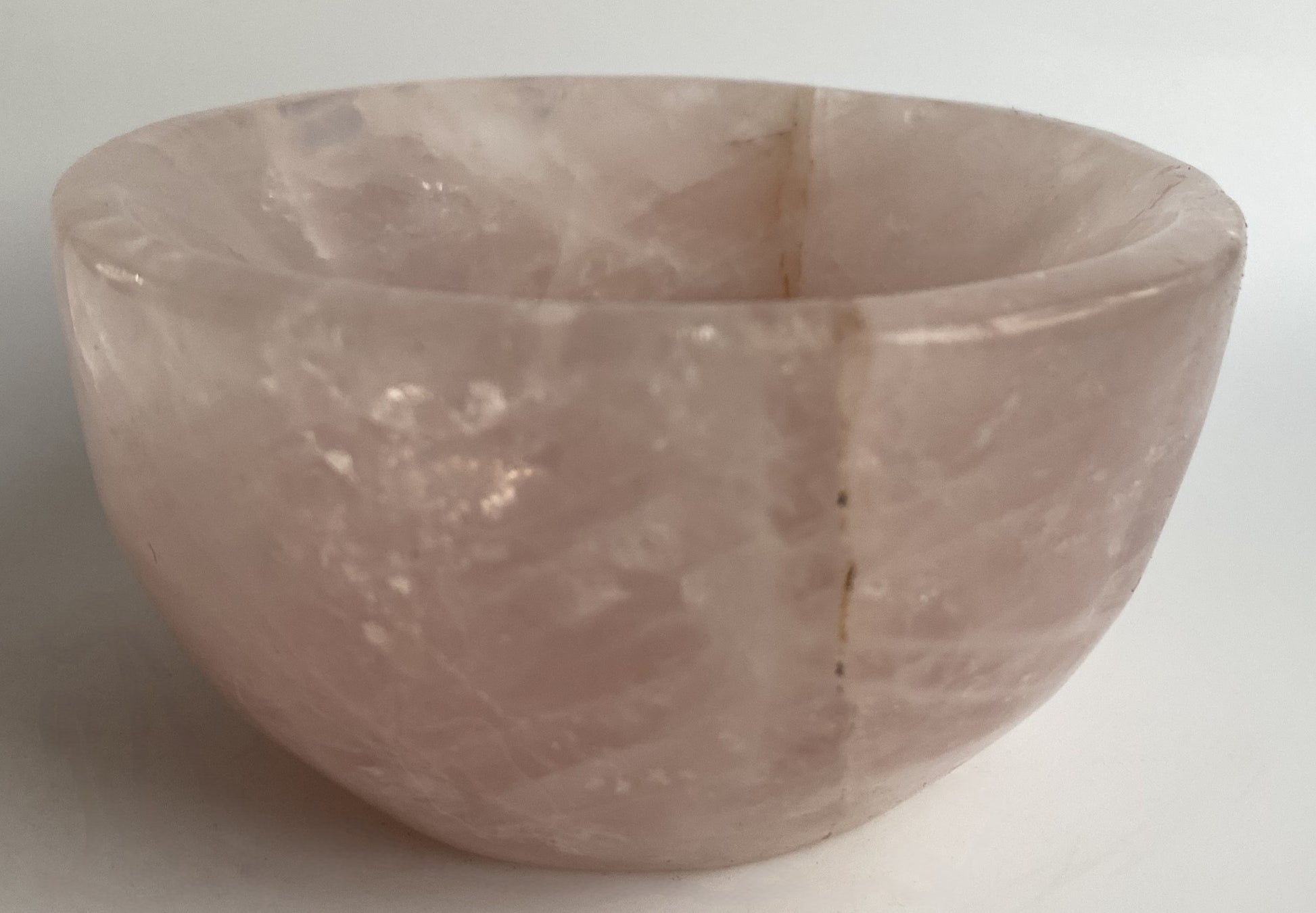 Bol din cristal de cuart roz pe fundal alb sub lumina naturala