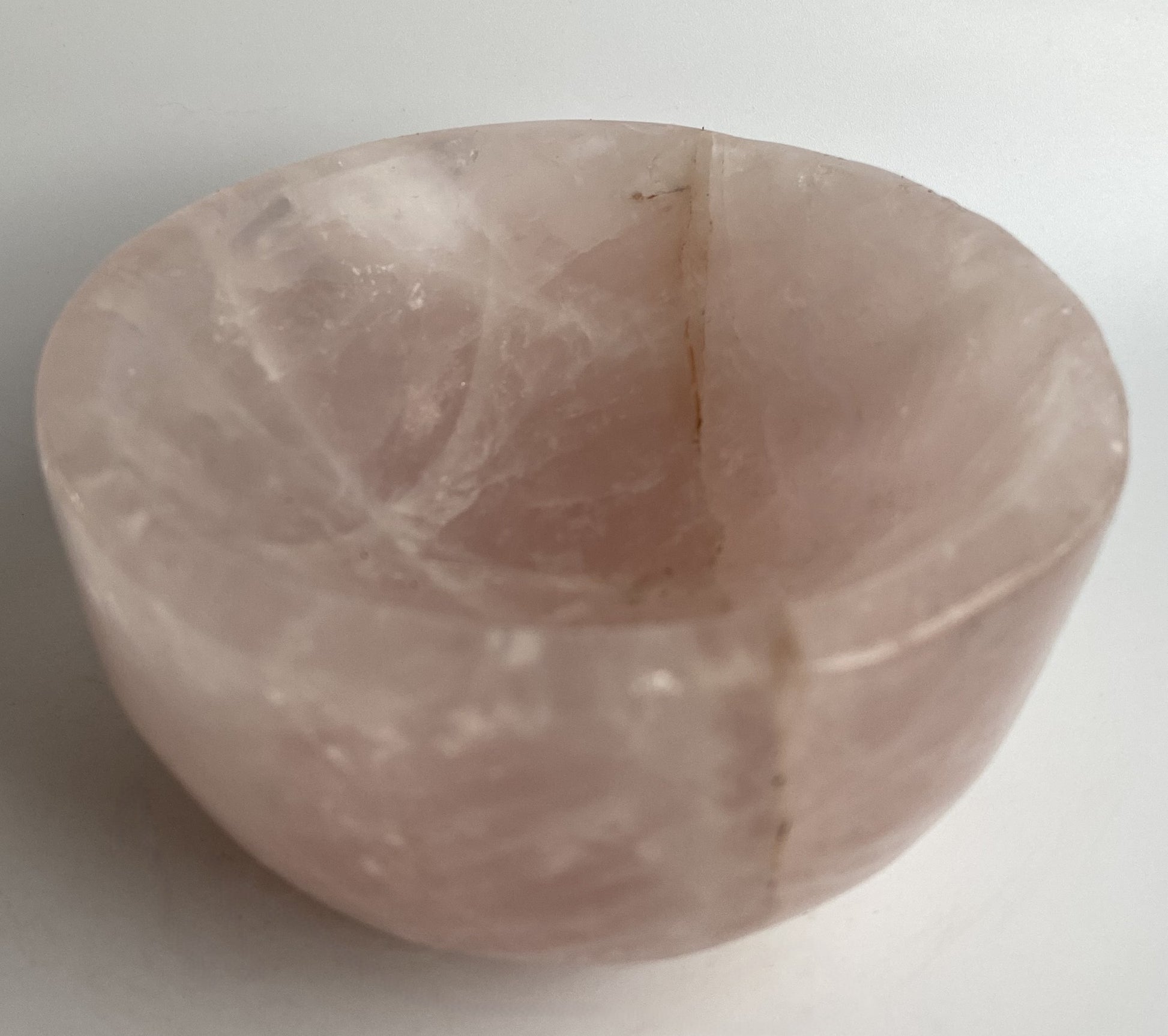 Bol din cristal de cuart roz pe fundal alb sub lumina naturala