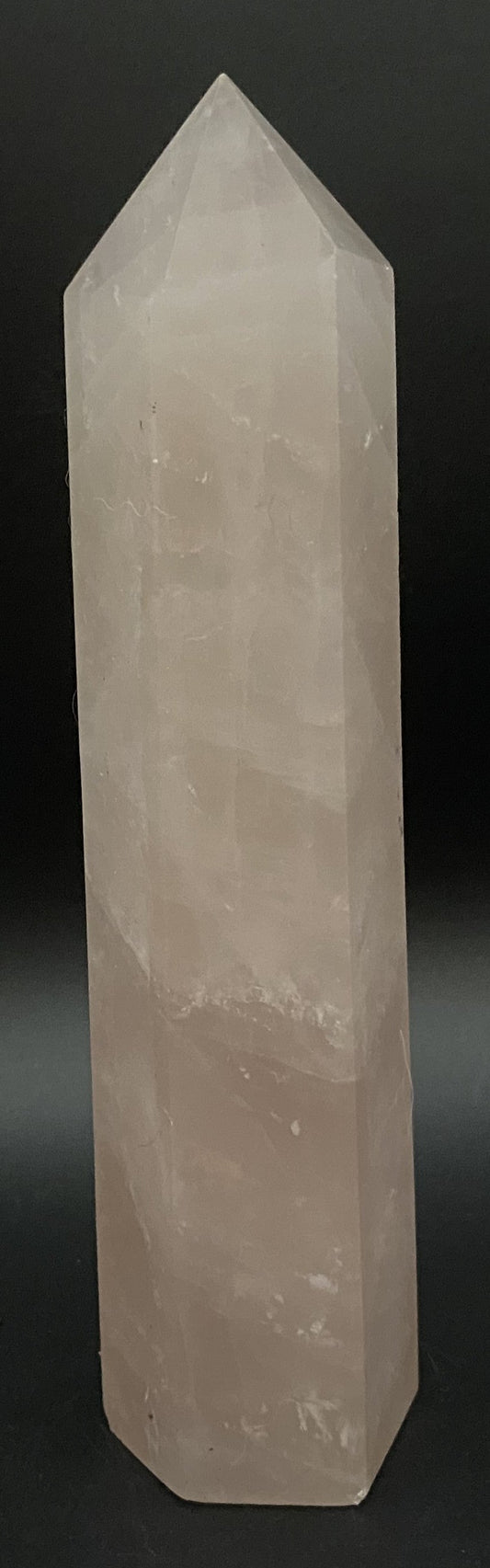 Obelisc de 15.5 cm din cristal de cuart roz pe fundal negru sub lumina artificiala