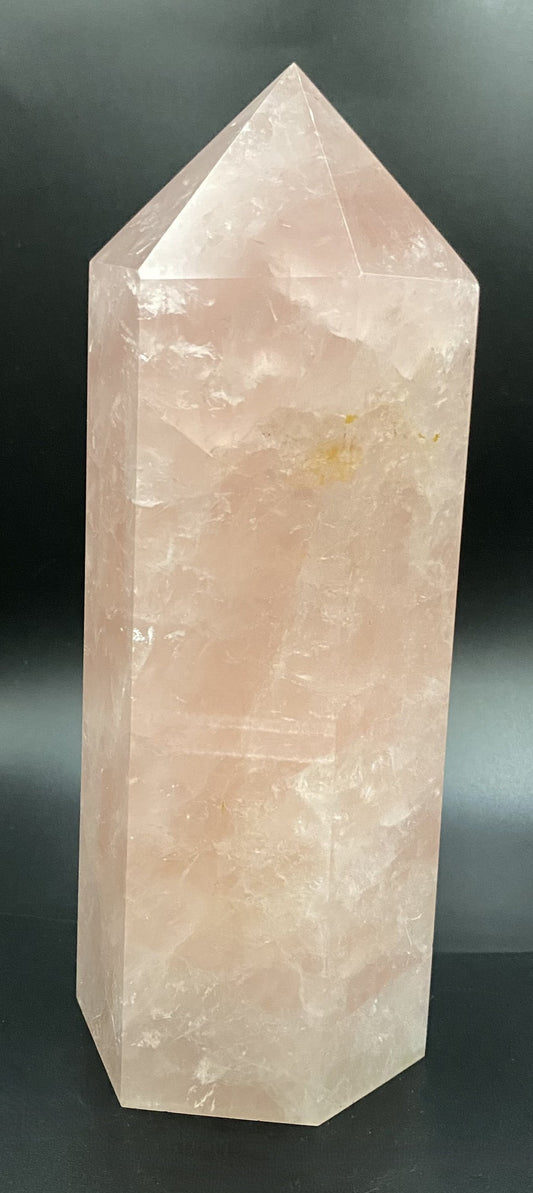 Obelisc de 20 cm din cristal de cuart roz pe fundal negru sub lumina artificiala