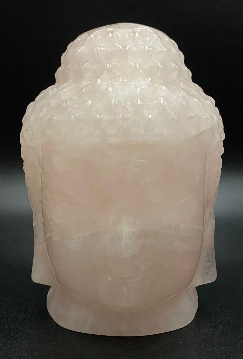 Sculptura Buddha din cuart roz pe fond negru sub lumina artificiala