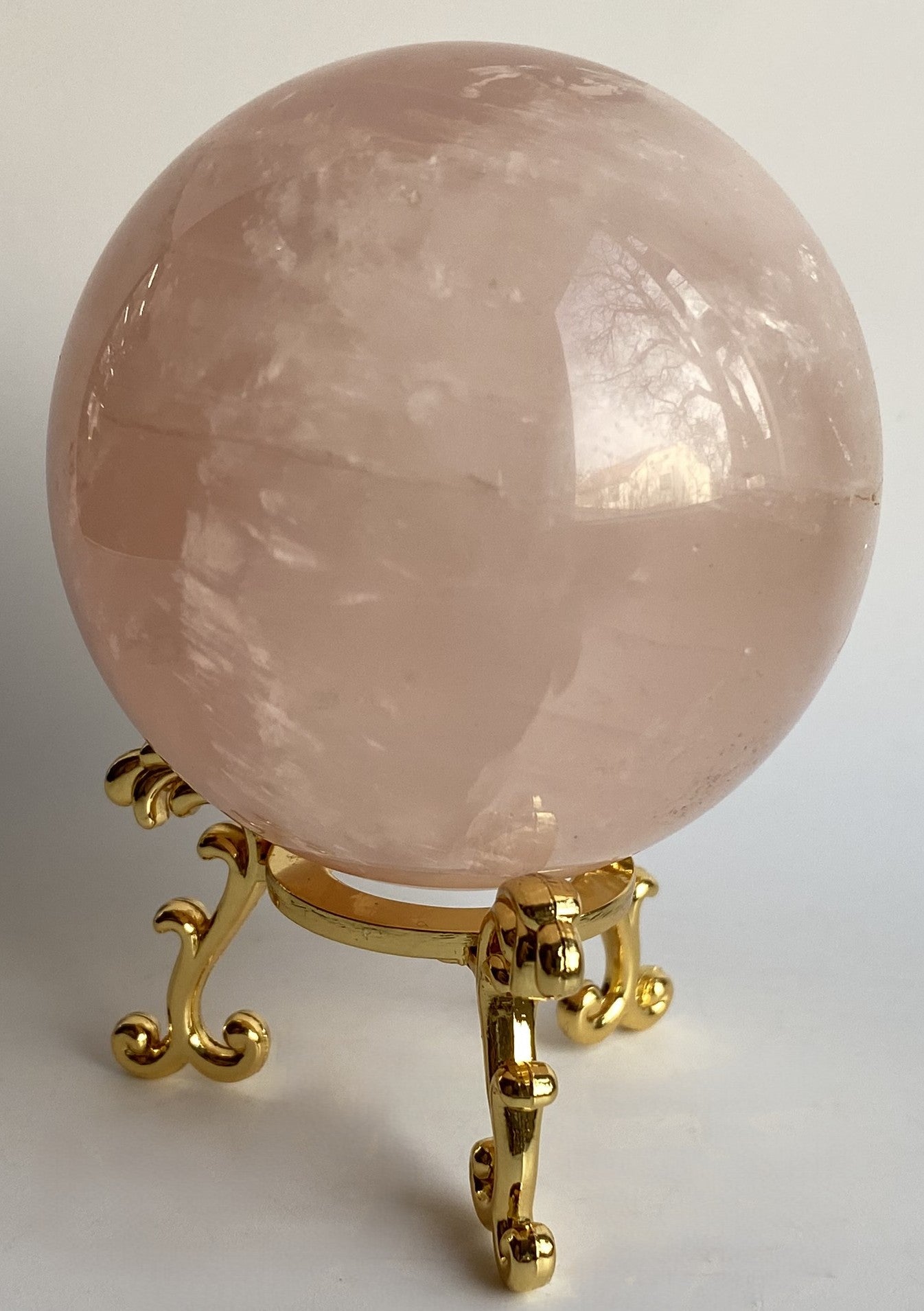 Sfera din cristal de cuart roz pe suport metalic cu fundal alb