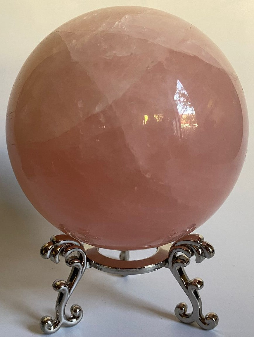 Sfera din cristal de cuart roz pe suport metalic cu fundal alb