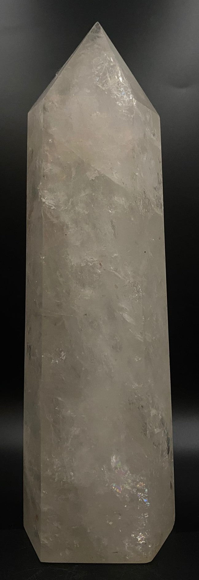 Obelisc de 22 cm din cuart transparent pe fundal negru sub lumina artificiala