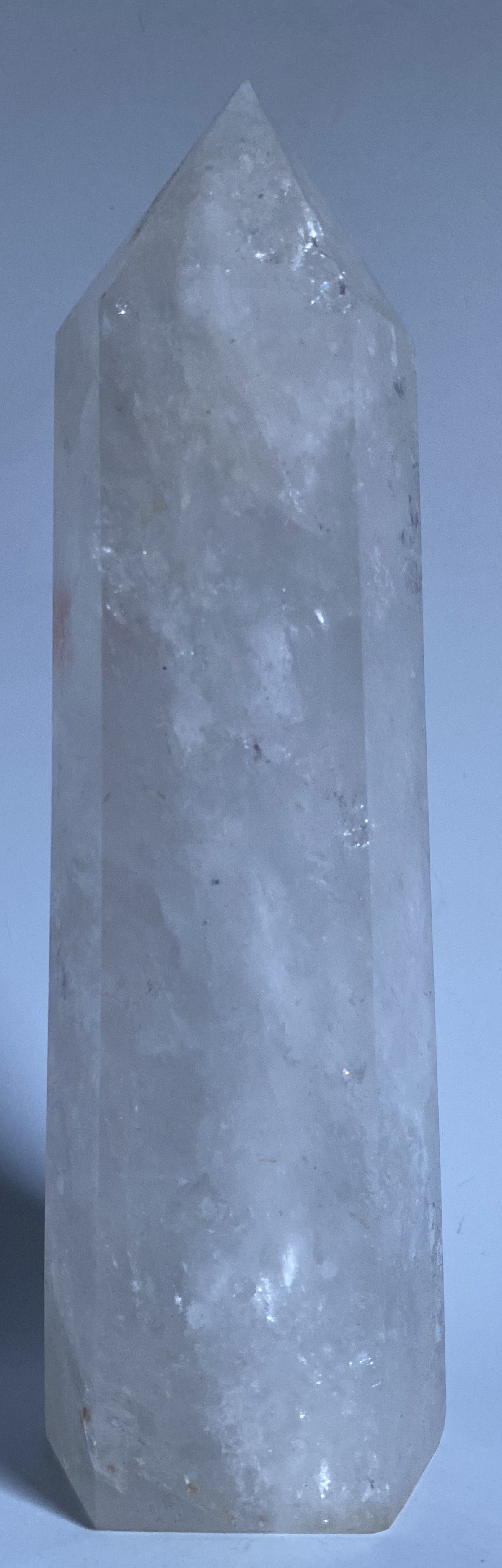 Obelisc de 22 cm din cristal de stanca pe fundal alb sub lumina naturala