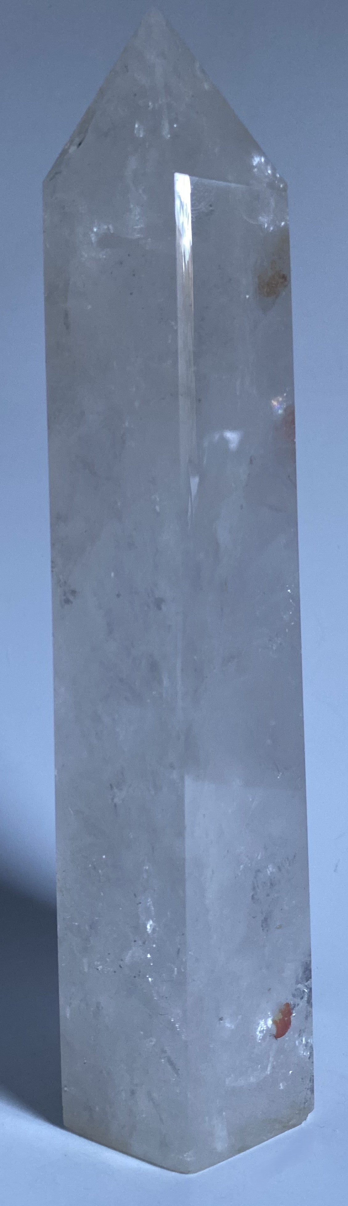 Obelisc de 22 cm din cristal de stanca pe fundal alb sub lumina naturala