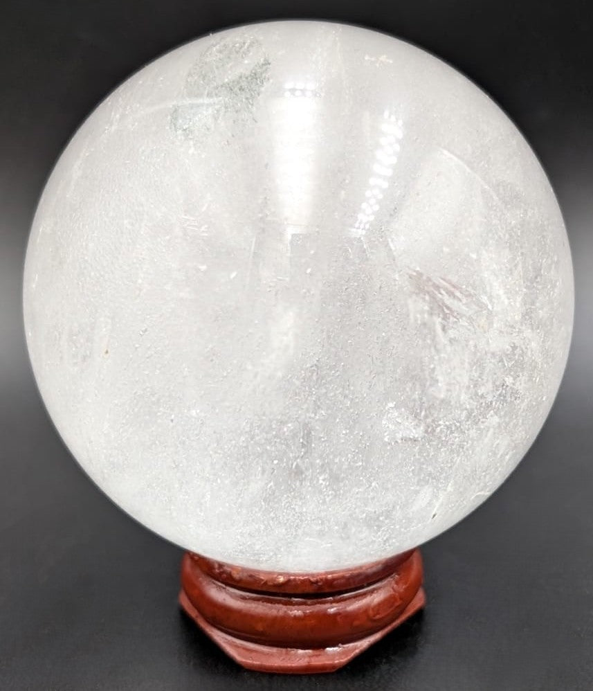 Sfera din piatra semipretioasa de cuart transparent pe suport din lemn cu fundal negru