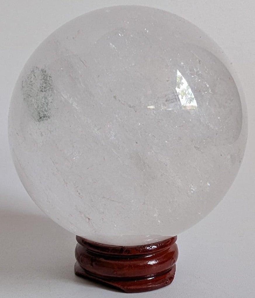 Sfera din cristal de cuart transparent pe suport din lemn cu fundal alb