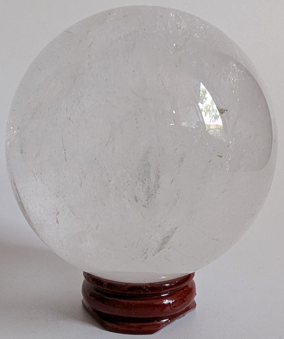 Sfera de 6.2cm din cristal de cuart transparent pe suport din lemn cu fundal alb
