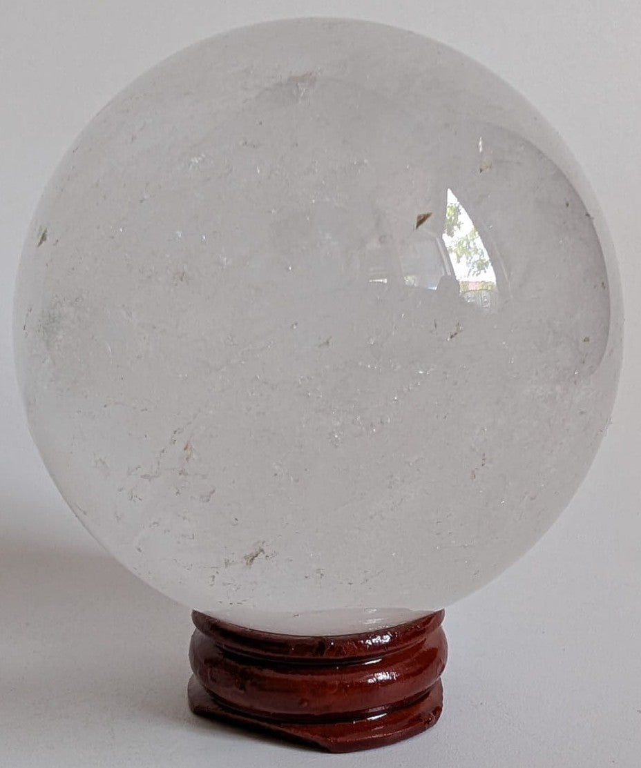Sfera decorativa de 6.2cm din cristal de cuart transparent pe suport din lemn cu fundal alb