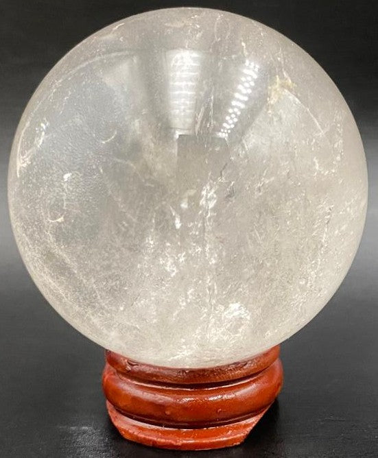 Sfera din piatra semipretioasa de cuart transparent pe suport din lemn cu fundal negru
