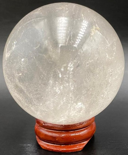 Sfera din piatra semipretioasa de cuart transparent pe suport din lemn cu fundal negru