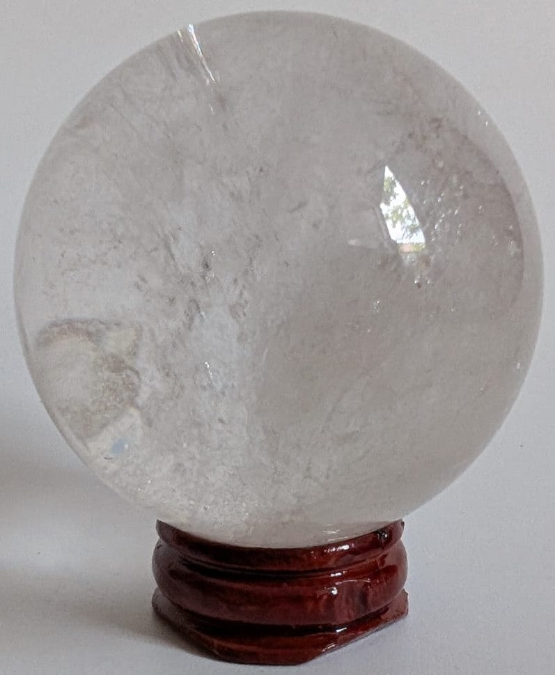 Sfera de 5.4cm din piatra semipretioasa de cuart transparent pe suport din lemn cu fundal alb