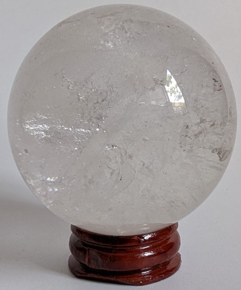 Sfera de 5.4cm din cristal de cuart transparent pe suport din lemn cu fundal alb