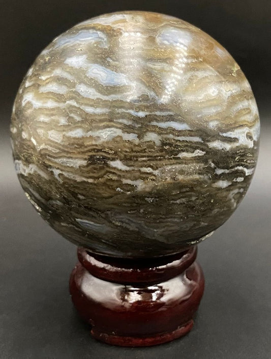 Sfera din piatra semipretioasa de simbiot de fluorit cu agat pe suport din lemn cu fundal negru 