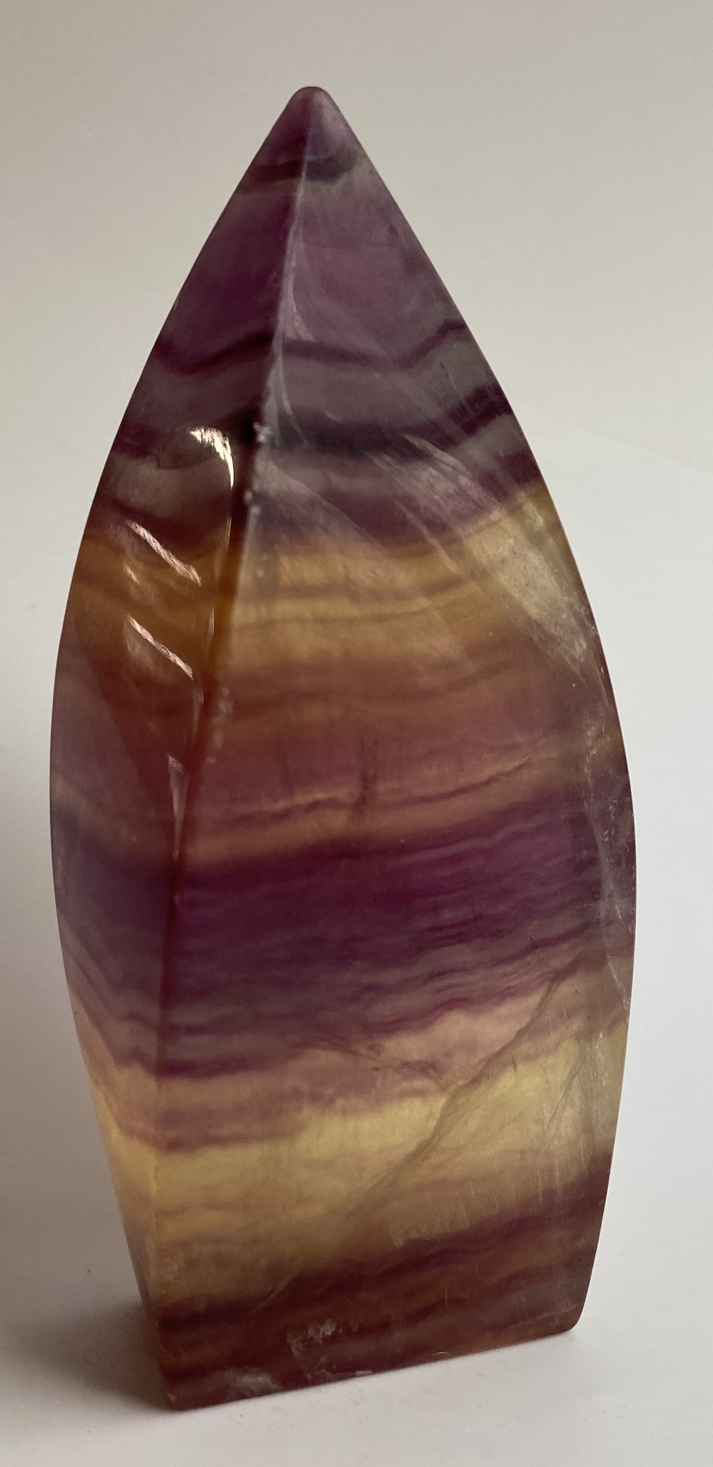 Sculptura din cristal de fluorit candy pe fundal alb sub lumina naturala