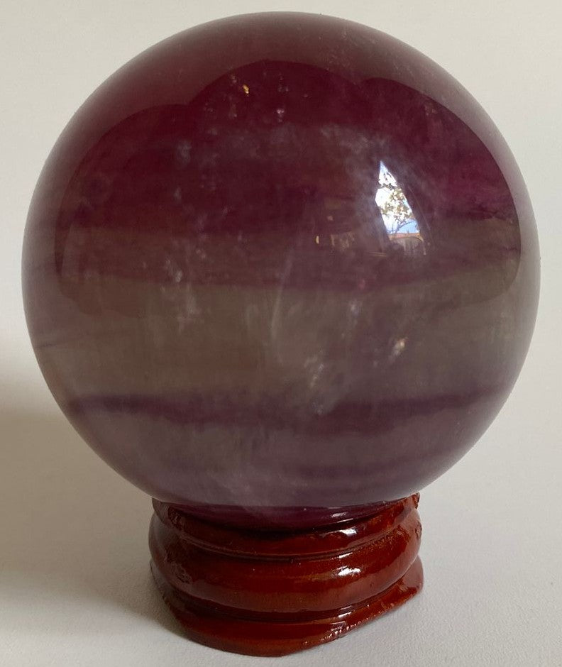Sfera din cristal de fluorit candy pe suport din lemn cu fundal alb