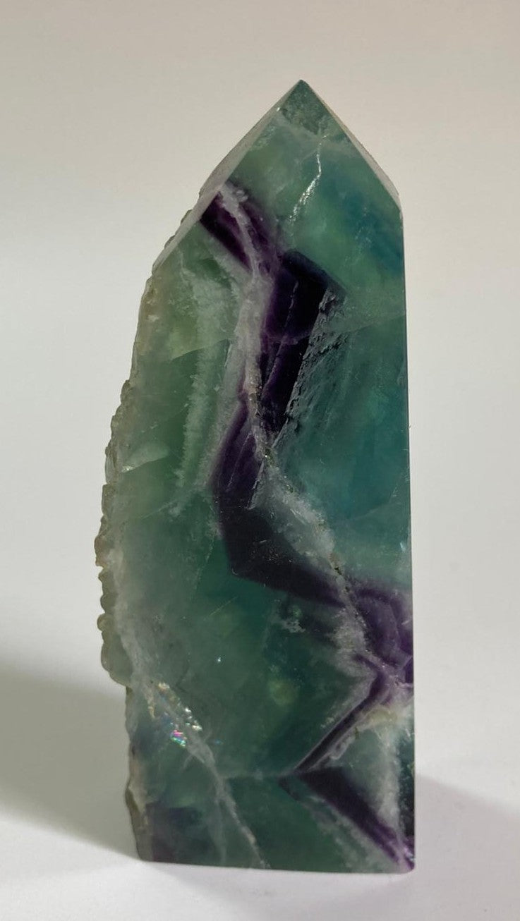 Obelisc brut de 10.7cm din piatra semipretioasa de fluorit rainbow pe fundal alb